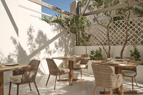 a patio with wooden tables and chairs and trees at Utopia Hotel in Koufonisia