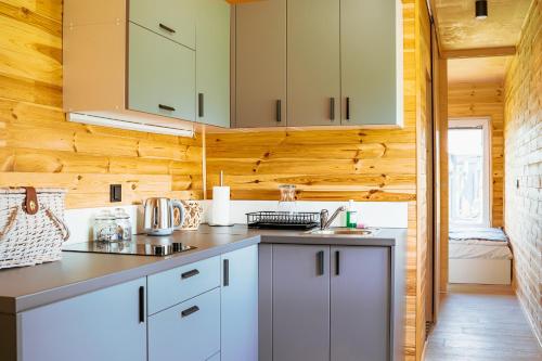 a kitchen with white cabinets and wooden walls at Arche Siedlisko Piłka Boisko 