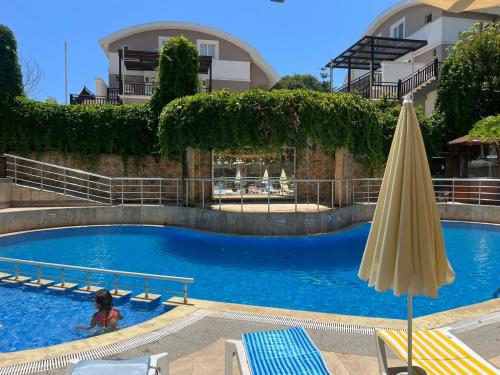 a swimming pool with an umbrella and a person in the water at RK MAGİC DREAM HOTEL in Kemer