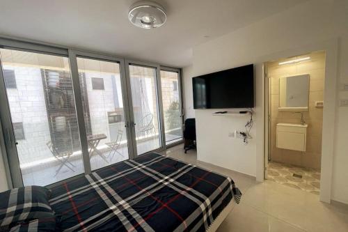 1 dormitorio con 1 cama, TV y ventanas en luxury boutique apartment 2BR With balcony on the sea, en Haifa