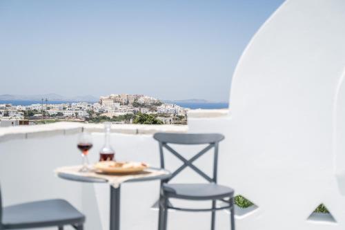 una mesa con 2 sillas y una copa de vino en el balcón en Disis Residence, en Naxos Chora
