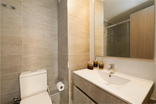 Un baño con lavabo, inodoro y espejo. en departamentos los mirlos, en Viña del Mar