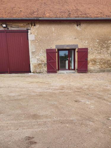 een gebouw met twee rode deuren en een raam bij Le domaine des Reverets in Trézelles