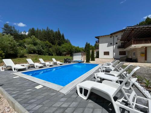 a swimming pool with white lounge chairs next to a house at Villa Green Heaven in Sarajevo