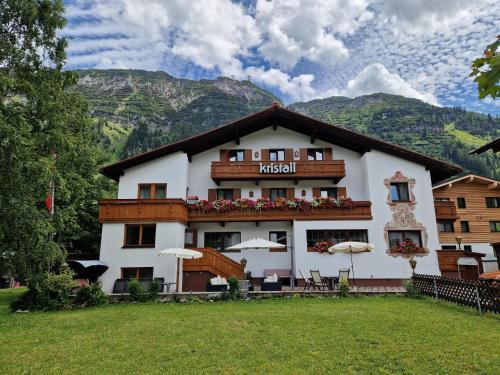 a large white building with mountains in the background at Hotel Kristall in Lech am Arlberg