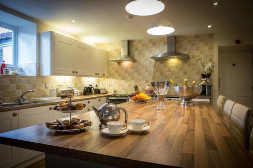 a kitchen with a wooden table with cups and dishes on it at Manor Farm Holiday Cottages in Reighton