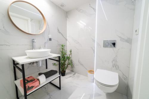 W białej łazience znajduje się umywalka i lustro. w obiekcie Apartamenty na Prusa w mieście Mikołajki