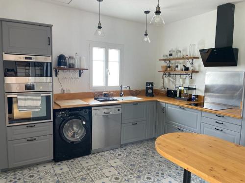uma cozinha com uma máquina de lavar roupa e uma mesa de madeira em Charmante Echoppe en pierre proche gare em Libourne