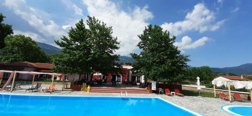 uma piscina em frente a uma casa com duas árvores em ΠΕΡΙ ΑΝΕΜΩΝ em Zérvi