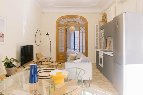 Aticco Living Gràcia - Apartments Rooftop في برشلونة: مطبخ وغرفة معيشة مع طاولة زجاجية