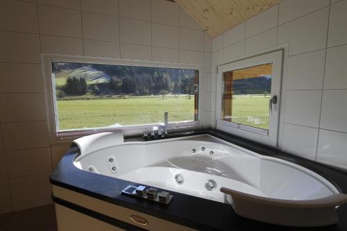 a bath tub in a bathroom with a window at Feriendorf Murau by ALPS RESORTS in Murau