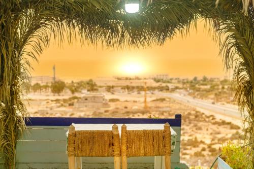 a bench sitting under a palm tree with a view of the desert at The Rina Hostel in Agadir