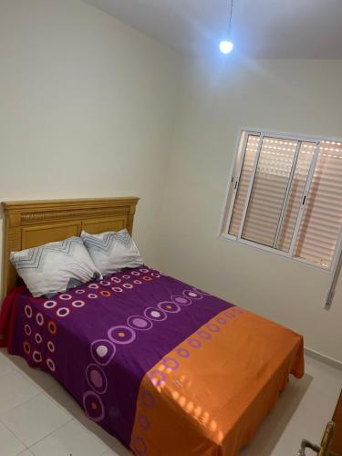 ein Bett mit einer lila Decke und einem Fenster in der Unterkunft Appartement saidia 2 chambres in Saidia 