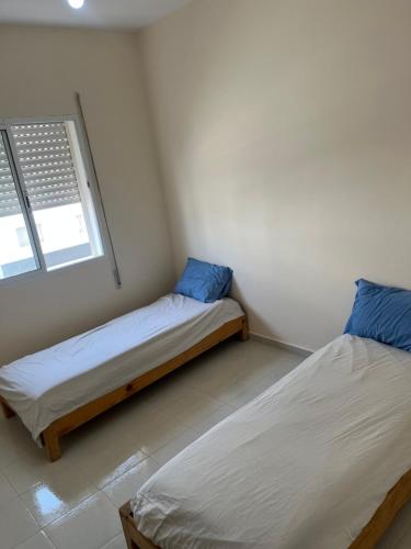 2 Betten in einem kleinen Zimmer mit Fenster in der Unterkunft Appartement saidia 2 chambres in Saidia 