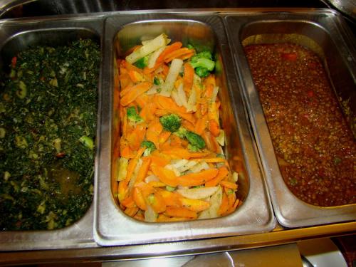 two metal trays of food with carrots and broccoli at ACK Guest House Nairobi in Nairobi