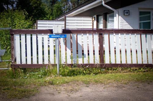 un cartello stradale di fronte a una recinzione bianca di Santa's Row house a Rovaniemi