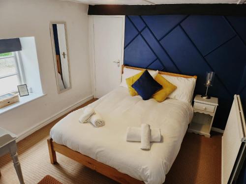 1 dormitorio con 1 cama grande y pared azul en The Fox Inn en Souldern