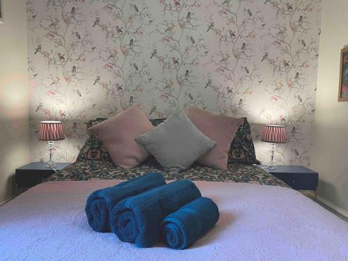 a bed with two blue pillows on top of it at West London stunning garden flat - period features in London