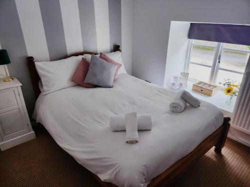 uma cama com lençóis brancos e toalhas em The Fox Inn em Souldern