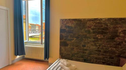 a room with a stone wall and a window at B&B -Di Piazza Cairoli in Pisa