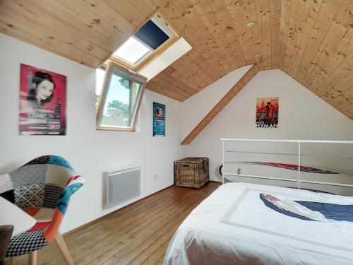 een slaapkamer op zolder met een bed en een raam bij Maison de vacances bord de mer in Plougrescant
