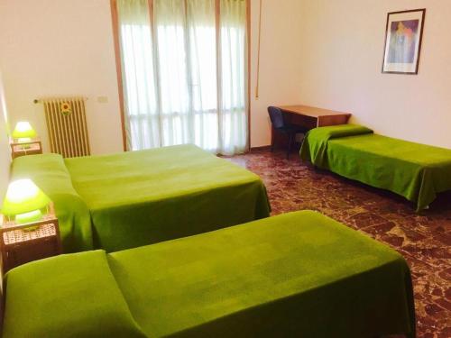 una habitación de hotel con 2 camas verdes y una mesa en B&B Francesco, en Pisa