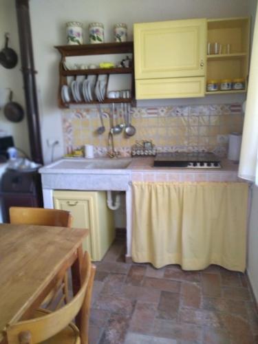 eine Küche mit gelben Schränken und einem Tisch darin in der Unterkunft Casa di montagna con spazio all'aperto 