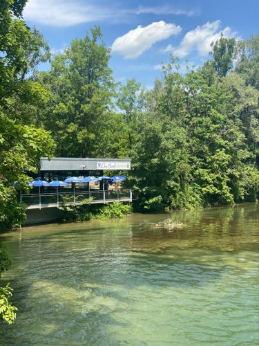 un puente sobre un río con árboles en el fondo en AllYouNeed Oktoberfest Basic Camping, en Múnich