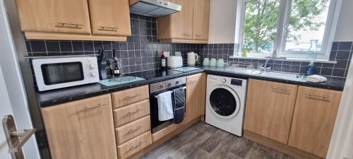 a kitchen with a microwave and a washer and dryer at The Pennington Apartment & FREE Parking Next to Sports Village in Leigh
