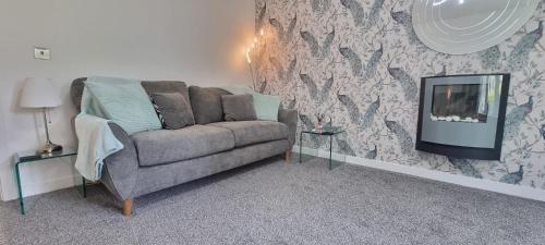 a living room with a couch and a tv at The Pennington Apt with Wifi and FREE Parking Next to Sports Village in Leigh