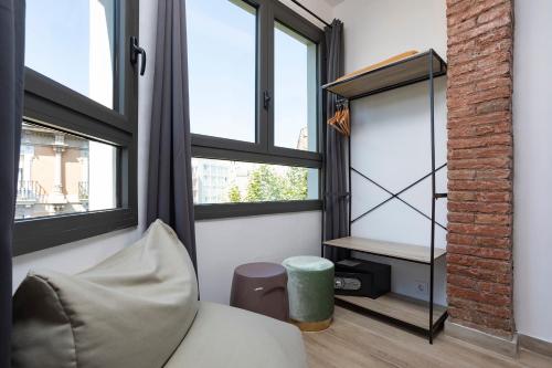 a room with windows and a couch and a stool at HOSTAL BEDMATES in Barcelona