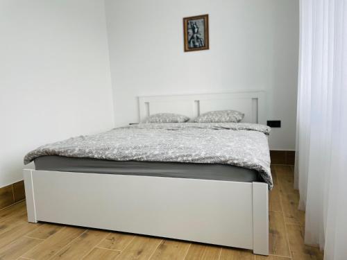 a white bed in a white room with a bed frame at Alto Turtas Apartamentai in Šiauliai