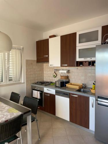 a kitchen with white appliances and a table and a tableablish at Apartman Elena in Verunić
