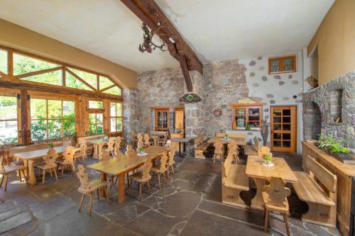 a restaurant with wooden tables and chairs and a stone wall at Steidlerhof in Bolzano