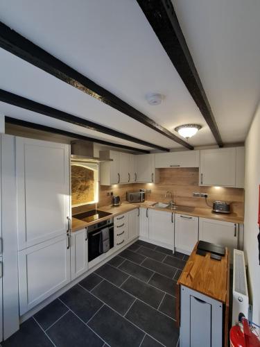 a large kitchen with white cabinets and a table at Puffin Cottage in Boddam