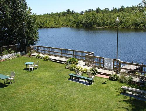 a park with benches and tables and a lake at Swiss Motel in Riverhead