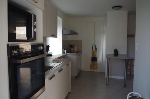 La cuisine est équipée de placards blancs et d'un four avec plaques de cuisson noires. dans l'établissement Domaine Joseph Lafarge Wine Resort - Lady's House - La maison de Michelle, à Lugny