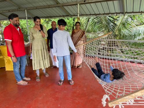 a group of people standing around a boy in a hammock at Marari Beach Villas in Mararikulam