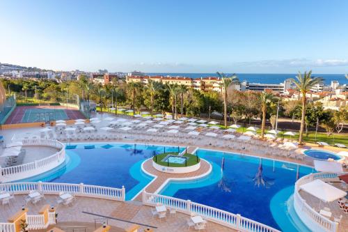 an aerial view of a resort pool with chairs and the ocean at Chatur Playa Real Resort in Adeje