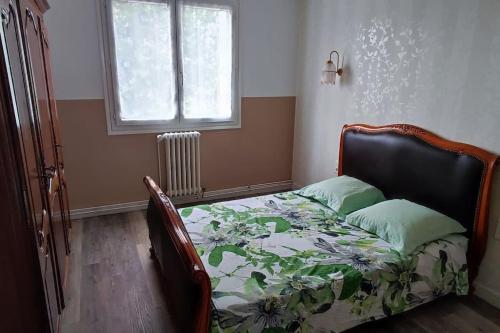 a bedroom with a bed with a flowered comforter and a window at Appartement T3 68 M2 Saint Avertin. in Saint-Avertin