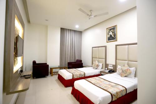 una habitación de hotel con 2 camas y una silla en HOTEL BLUE PEARL, en Bhopal