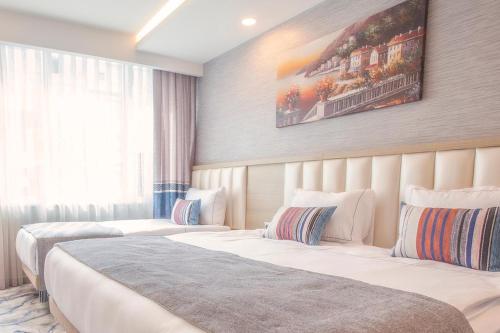 a hotel room with two beds and a painting on the wall at Old Town Point Hotel & Spa Antalya in Antalya