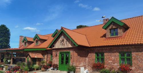a brick house with an orange roof at Osada Między Drzewami in Braniewo