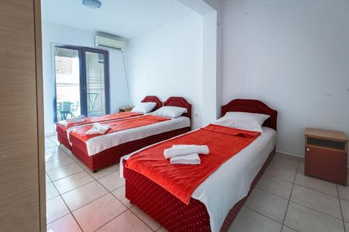 two beds in a room with red and white sheets at Prijevor Apartments in Budva