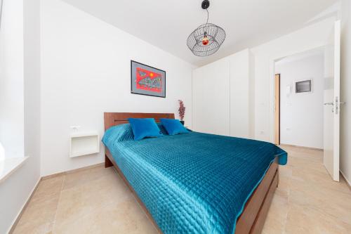 a white bedroom with a bed with blue sheets at Apartman Seaside 5 in Banjole