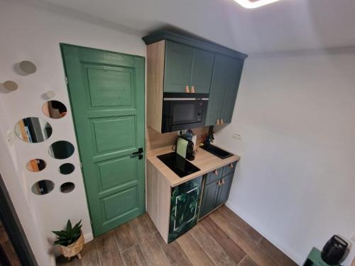 a small kitchen with green cabinets and a television at Tiny House 4 Two in Văliug