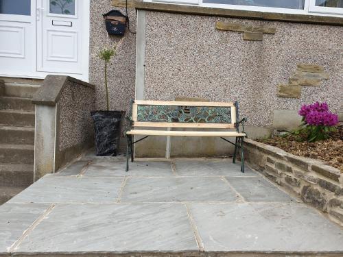 a wooden bench sitting in front of a house at Oakworth in Oakworth