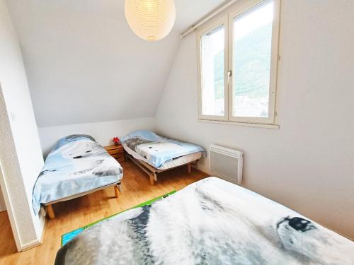 two twin beds in a room with a window at Chez Charlotte, T3 duplex, vue montagne, parking gratuit, 4 personnes in Luchon