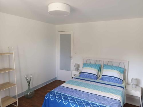 Chez Tartine في Thénioux: غرفة نوم مع سرير ووسائد زرقاء وبيضاء