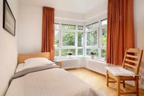 1 dormitorio con 1 cama, 1 silla y ventanas en Villa am Hang Wohnung 11 en Grömitz